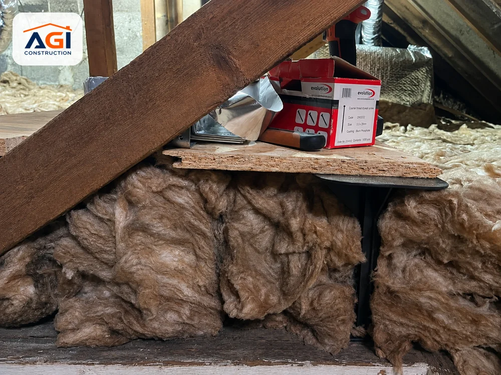 Mineral wool insulation packed between attic joists around timber roof structure